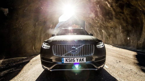 Black Volvo driving through a rocky tunnel